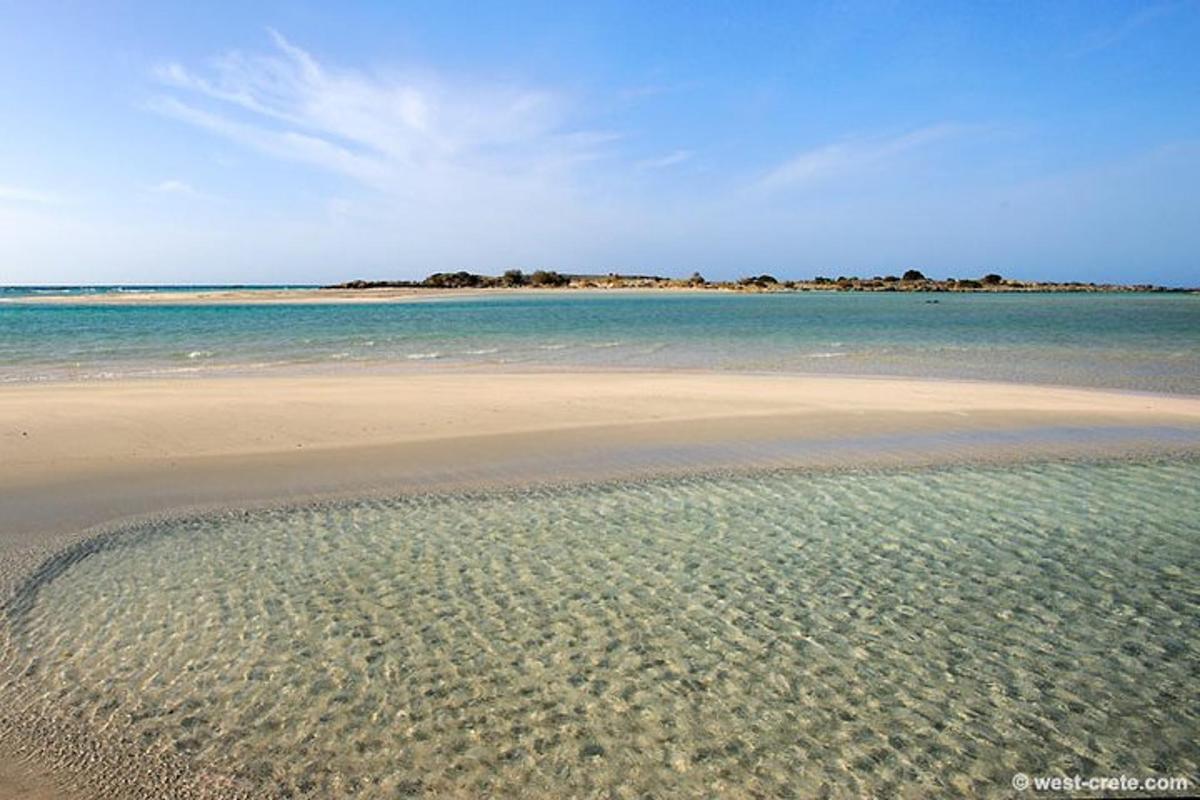 een strand met helder water en een eiland in de verte