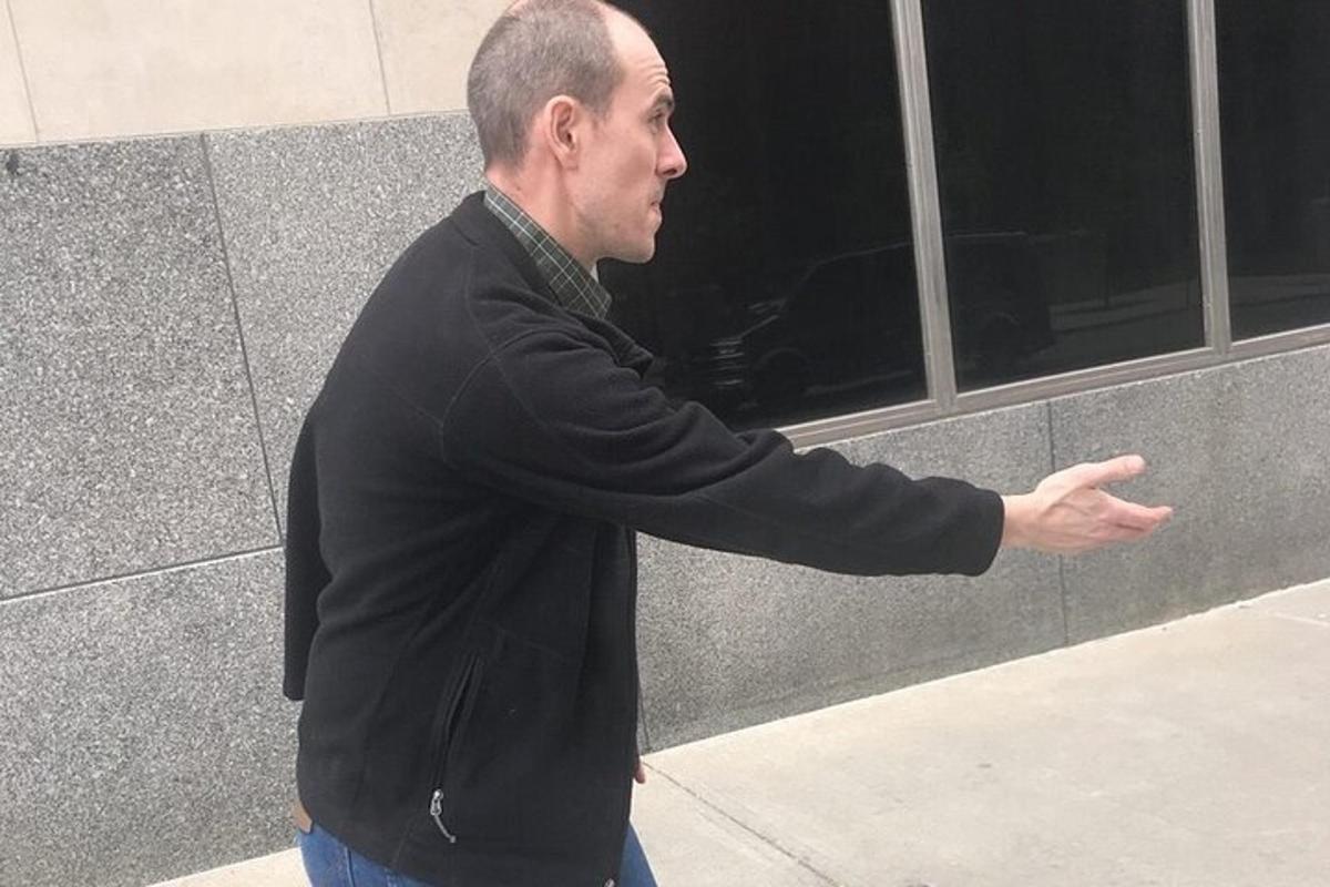 a man standing in front of a building with his hand out