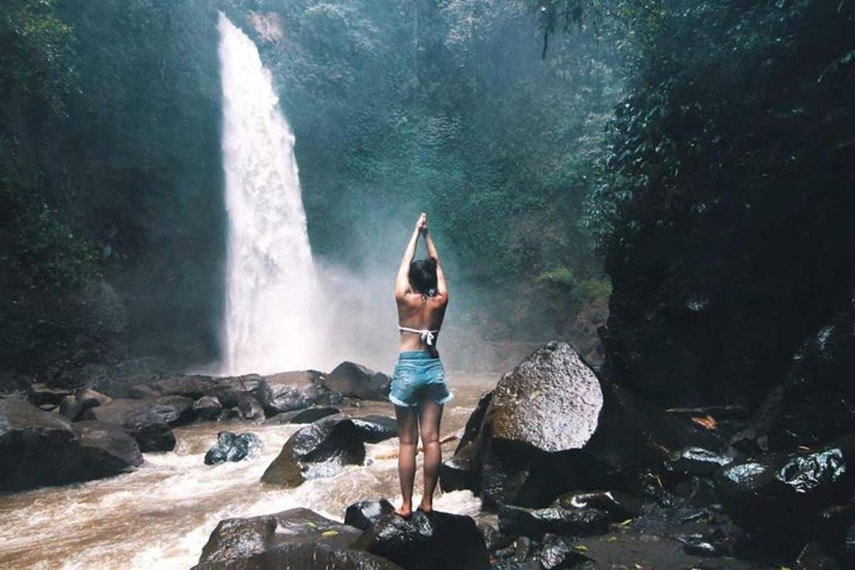 uma pessoa em pé sobre rochas em frente a uma cachoeira