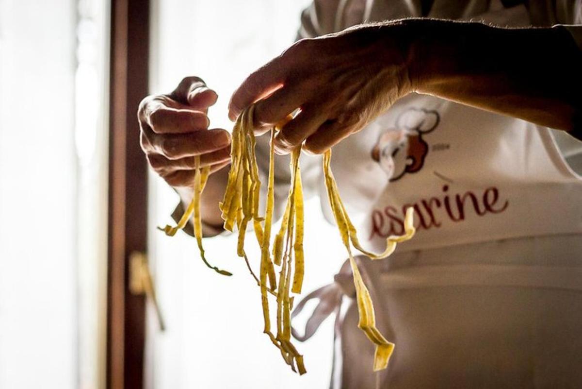 käsi, jossa on nippu keltaista pastaa