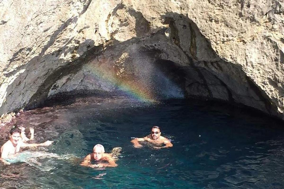 three men swimming in a cave with a rainbow