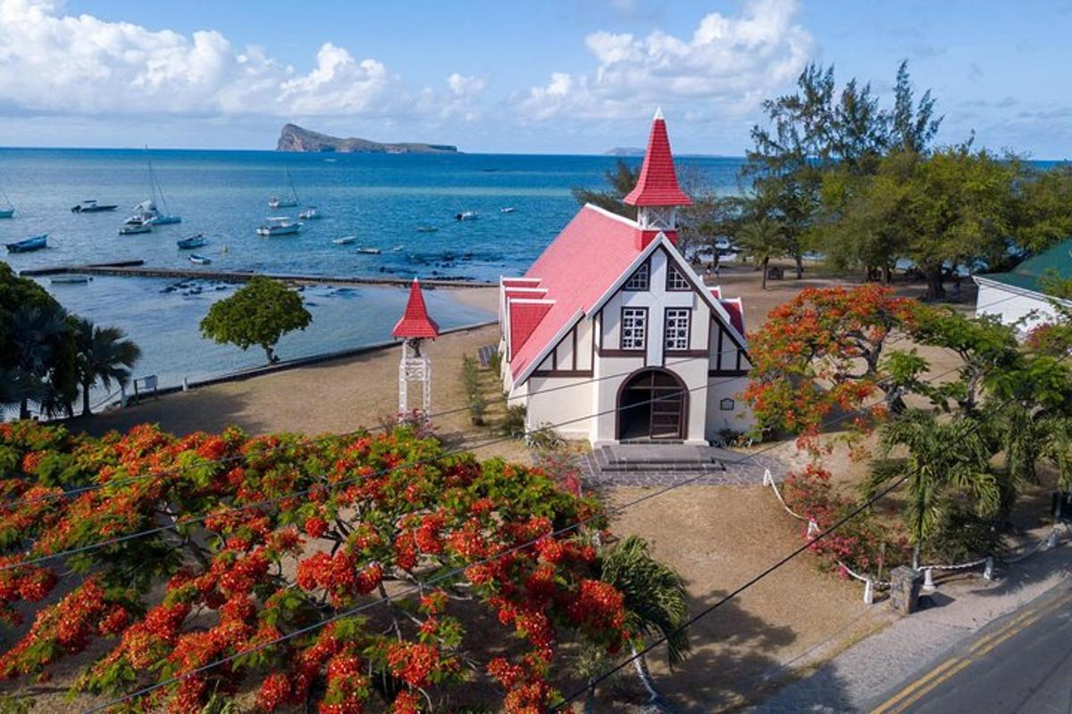 a house with red roofs and flowers in front of the water