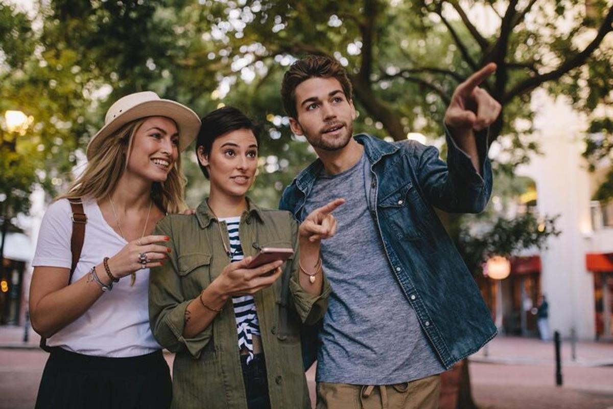 trijų žmonių grupė žiūri į mobilųjį telefoną