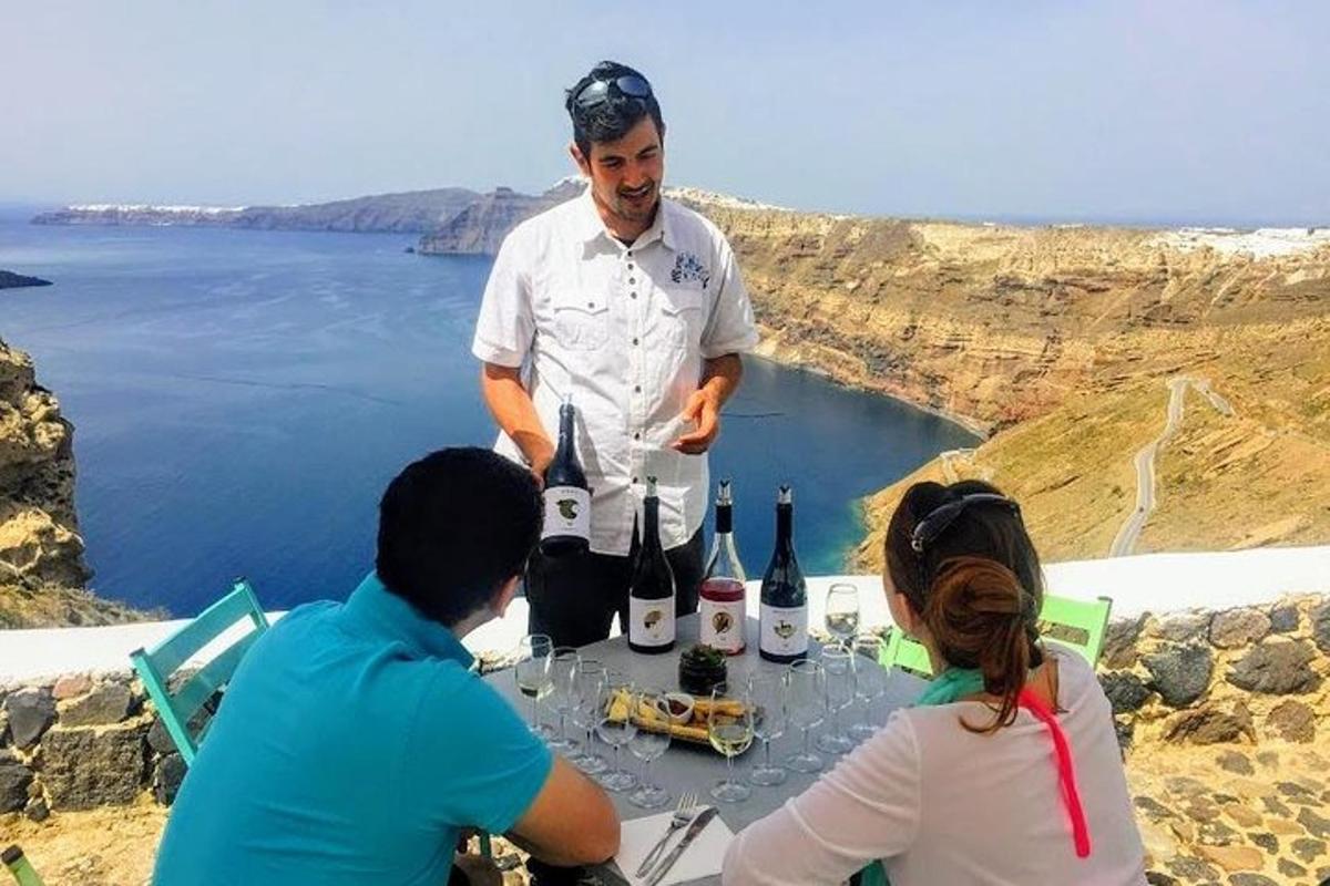 Un hombre de pie junto a una mesa con botellas de vino.