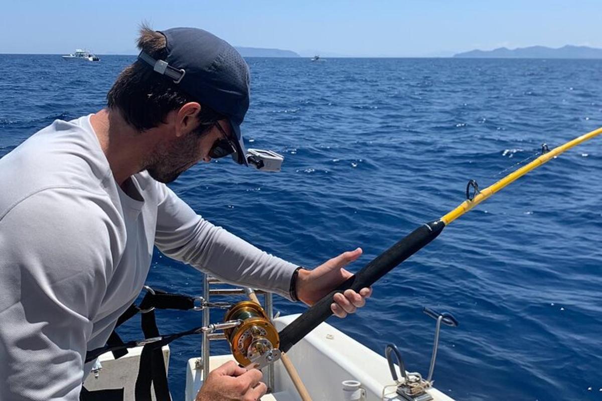 a man holding a fishing pole on a boat