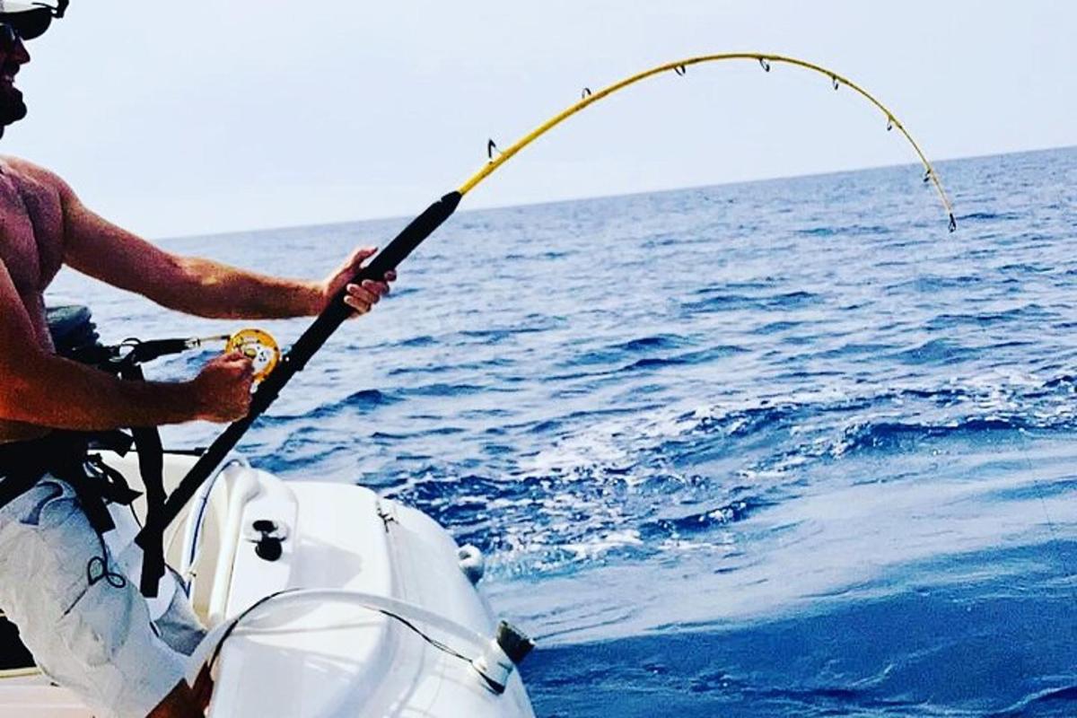 a man sitting on a boat holding a fishing rod