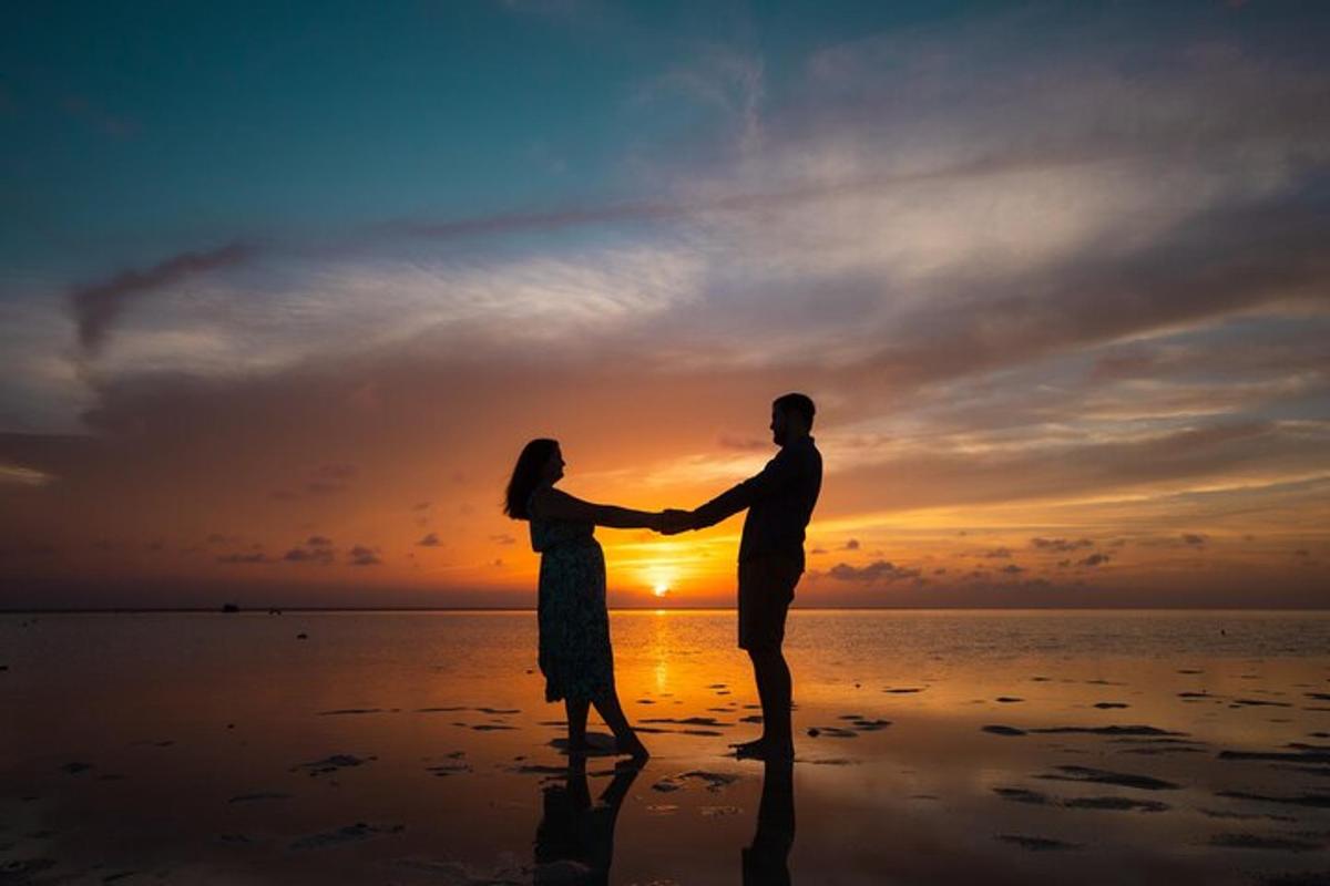Un hombre y una mujer de pie en la playa al atardecer