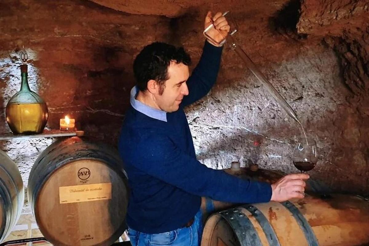 a man holding a glass of wine in a barrel
