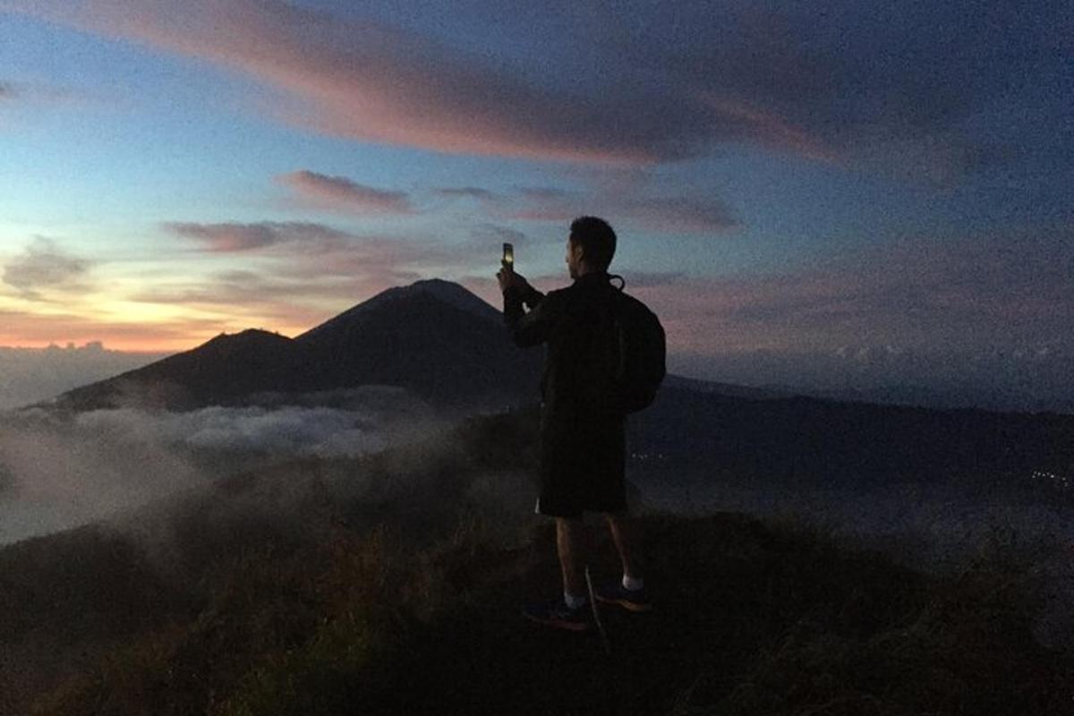 Ein Mann steht auf einem Berggipfel und macht ein Foto