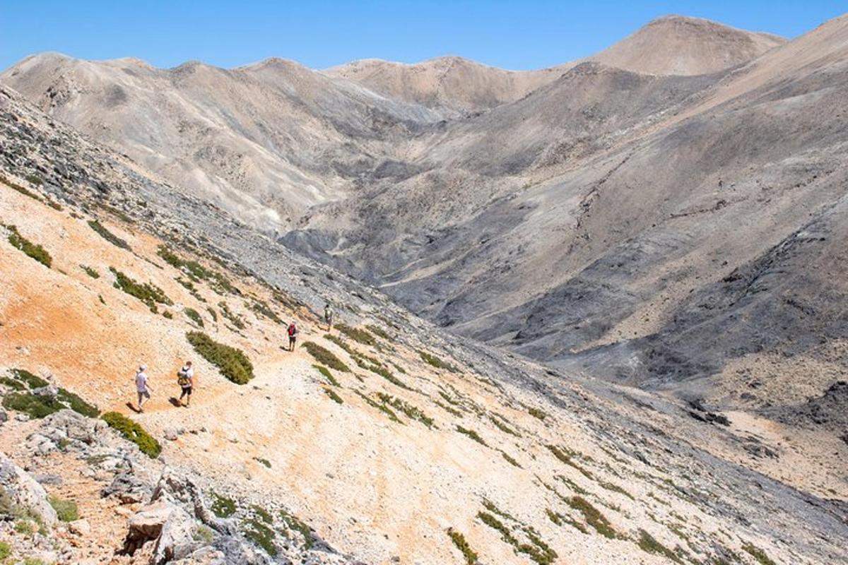 Δύο άνθρωποι περπατούν σε ένα βουνό με θέα μια κοιλάδα