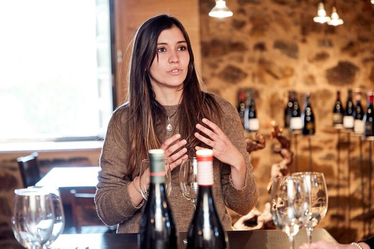 a woman sitting at a table with two bottles of wine