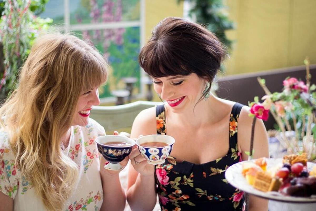 two women sitting at a table with a plate of food