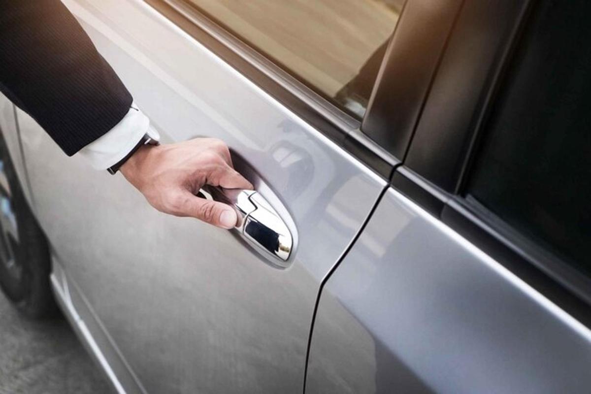 một bàn tay cầm chìa khóa giữ cửa xe