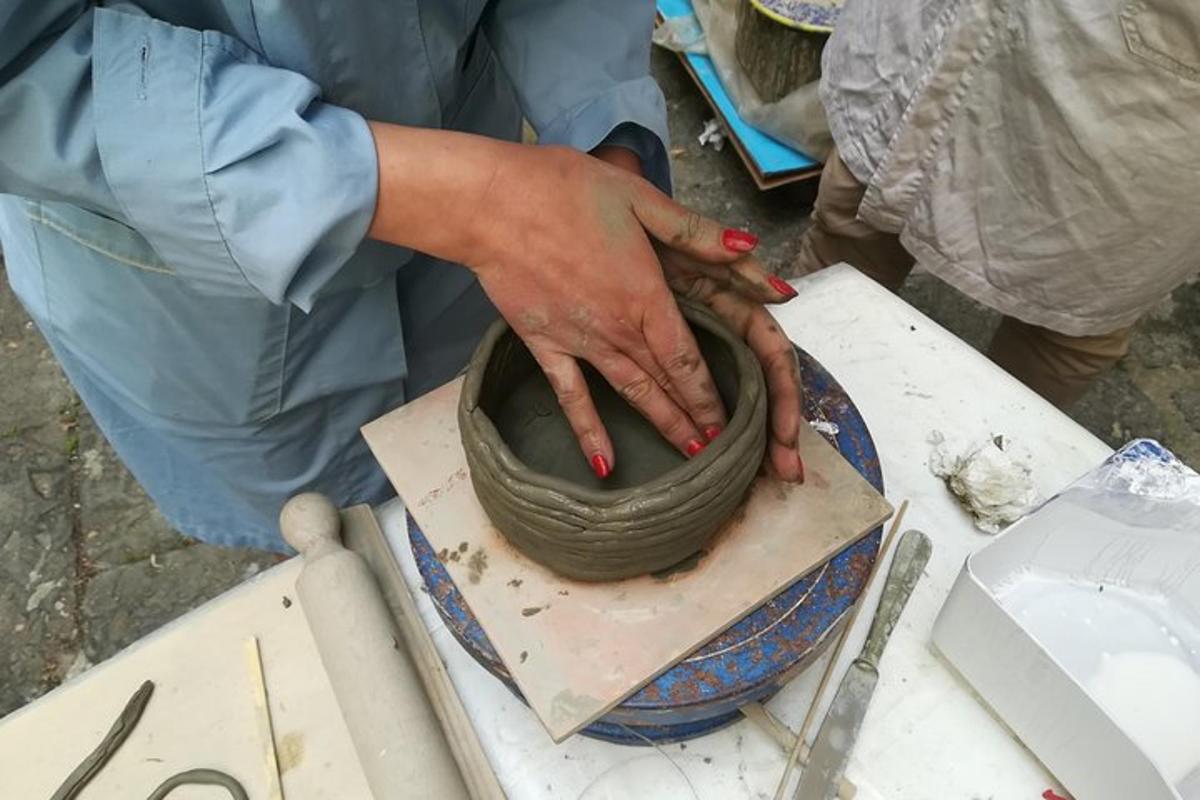 una persona haciendo una olla en un torno sobre una mesa