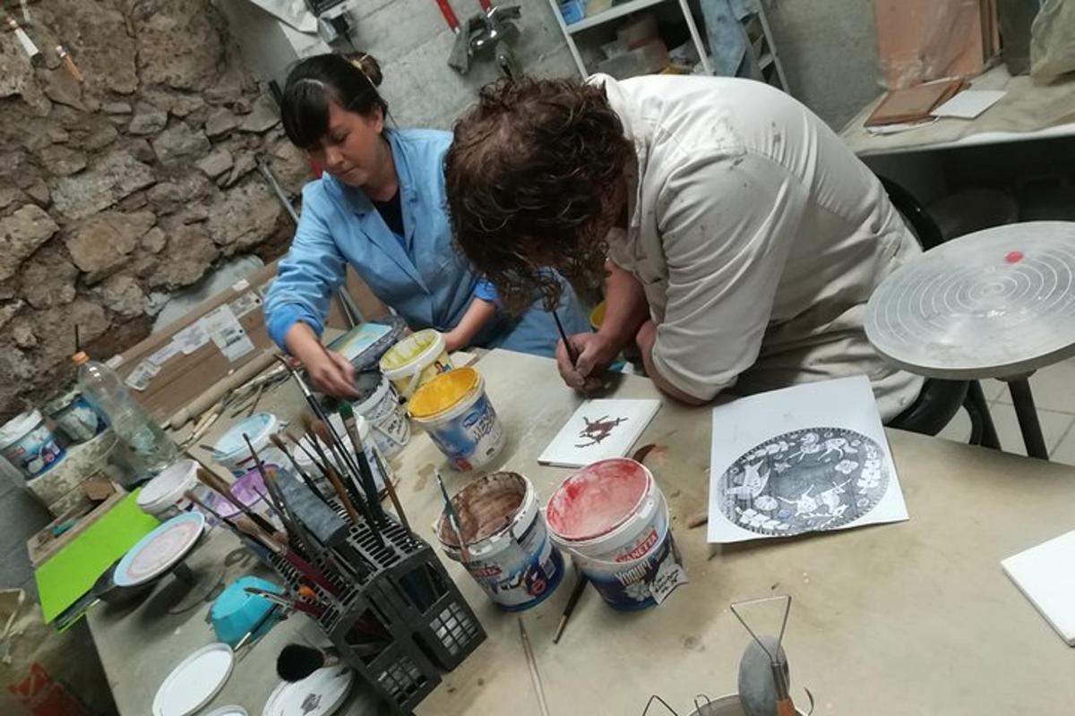Dos personas están trabajando en una pintura sobre una mesa.