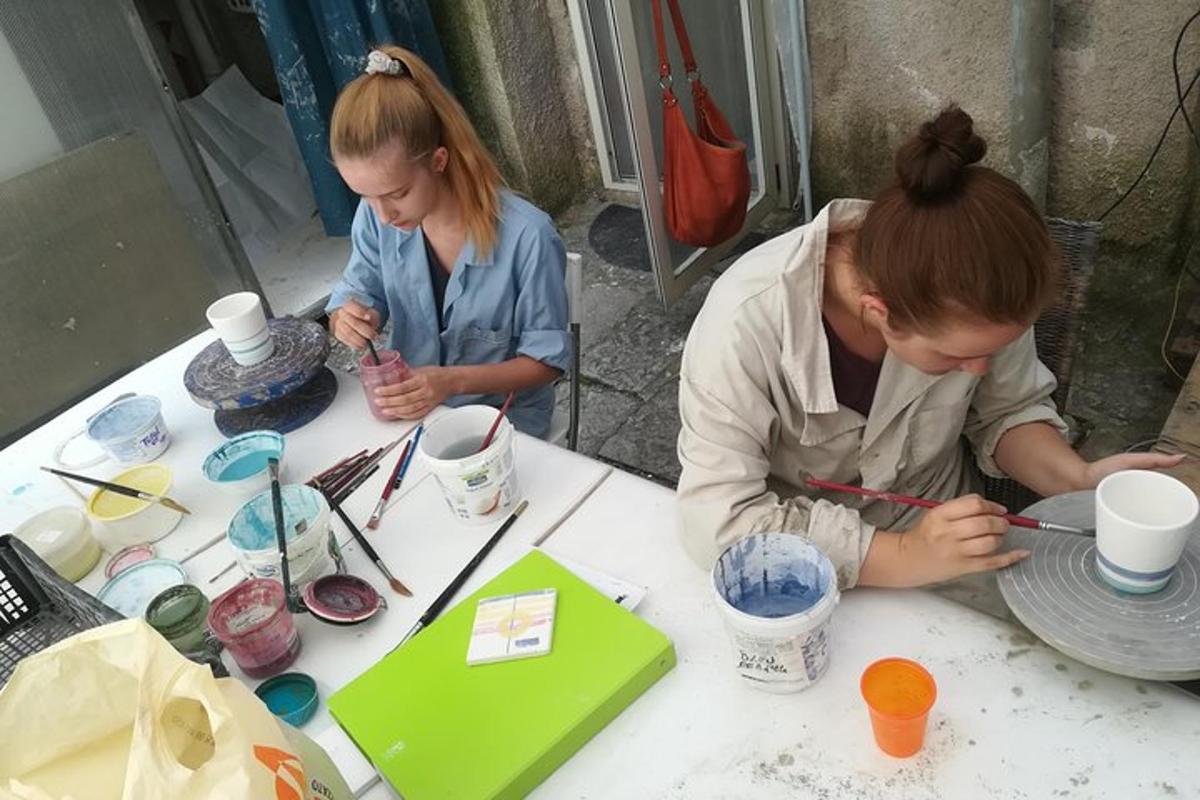 dvě ženy sedící u stolu a pracující s keramikou