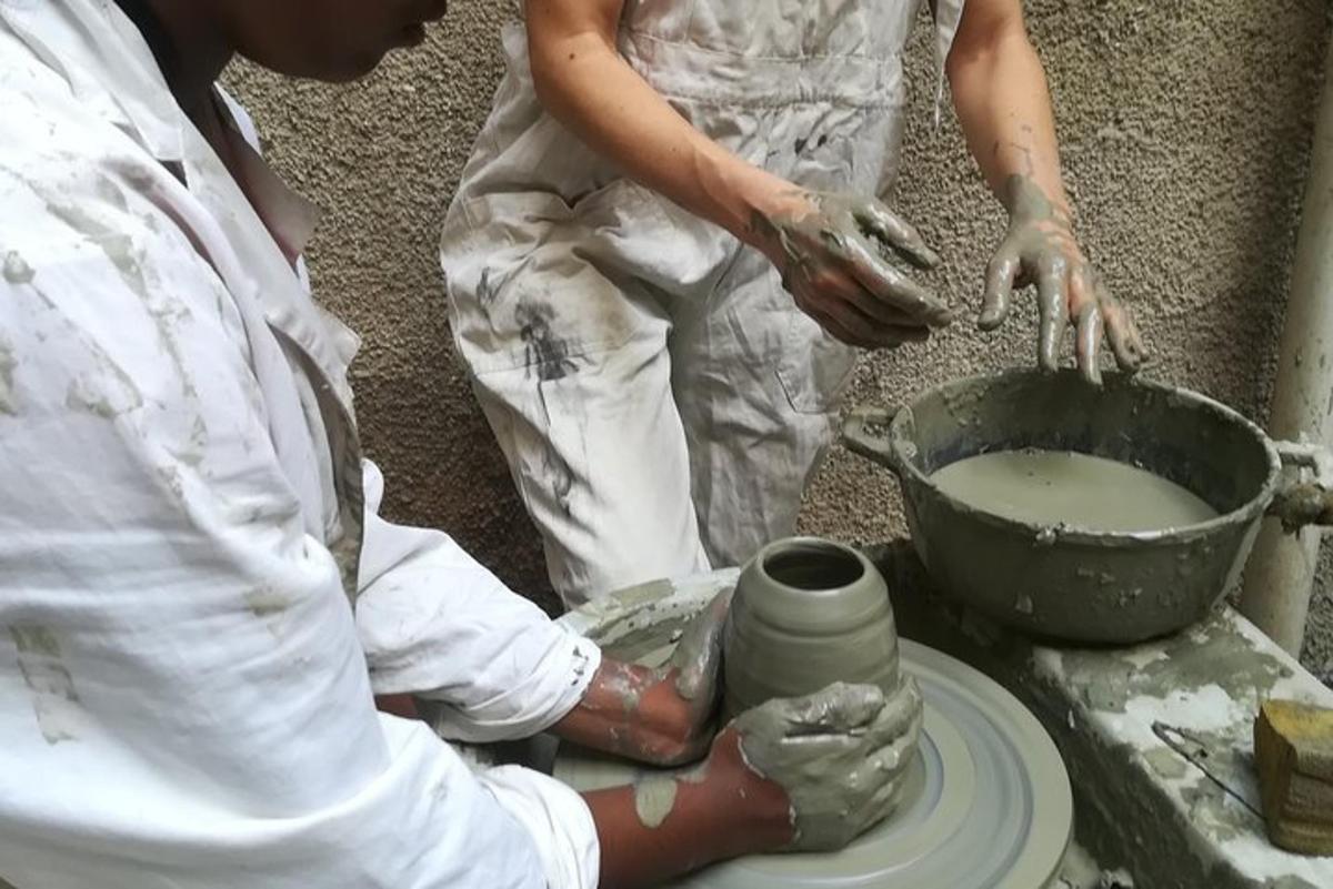 two women making a vase on a pottery wheel