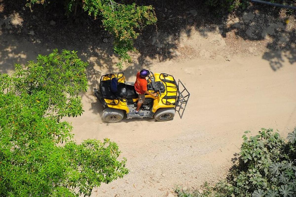 una persona che guida un quad giallo sulla spiaggia