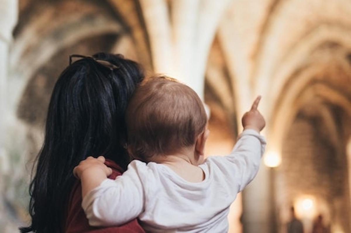en kvinde, der holder en baby og peger i en kirke
