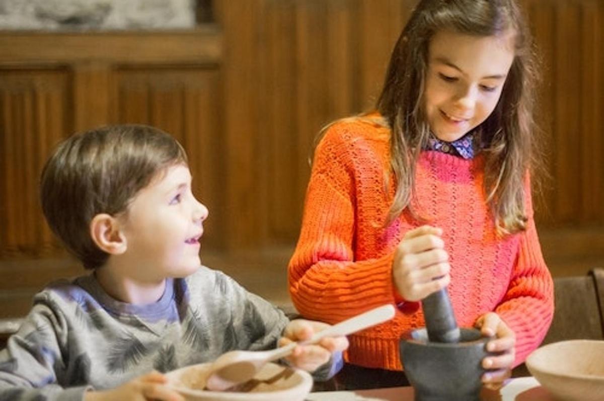 Una niña y un niño sentados en una mesa comiendo comida
