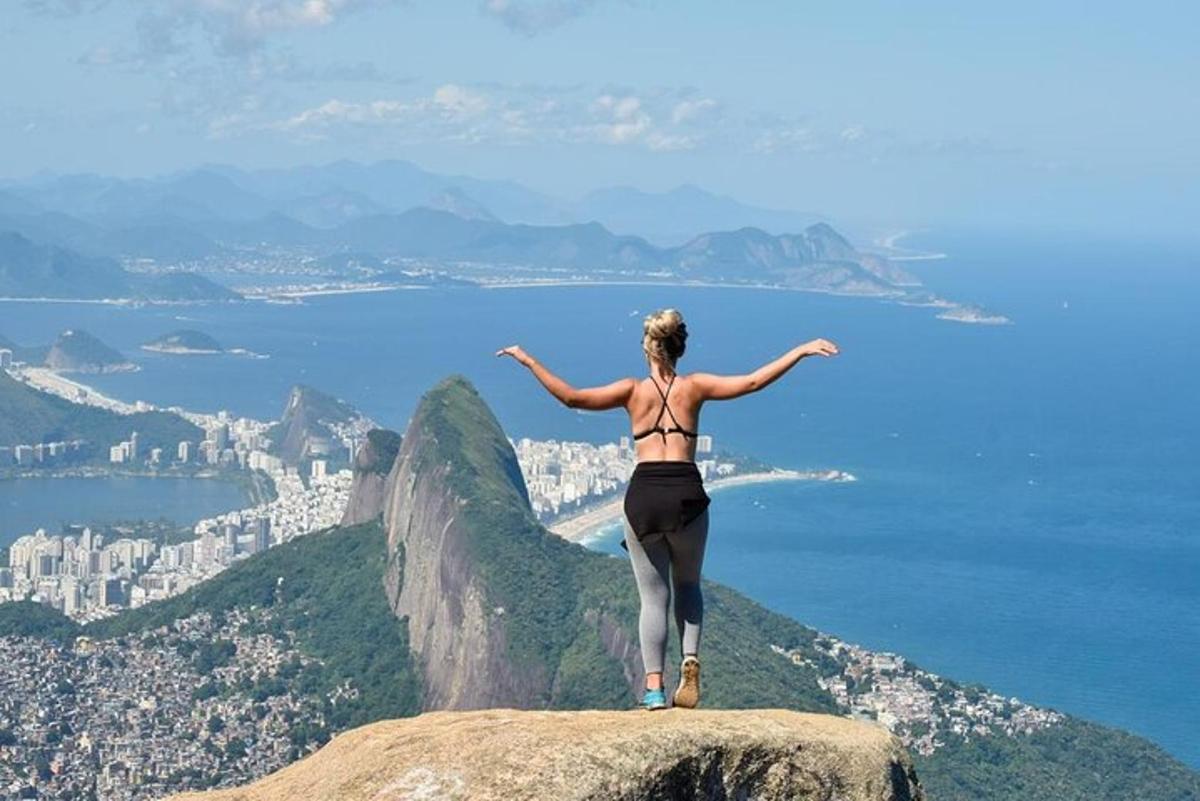 a woman standing on top of a rock overlooking the city