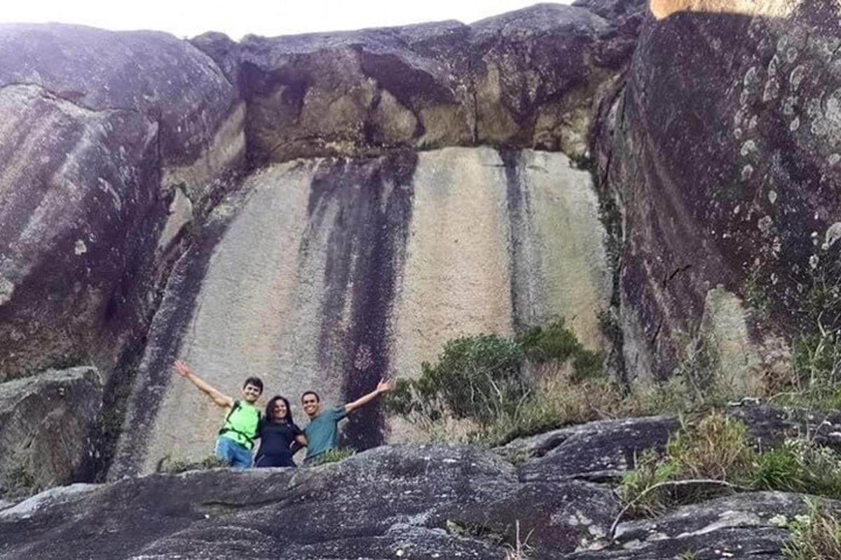 tiga orang berdiri di hadapan air terjun