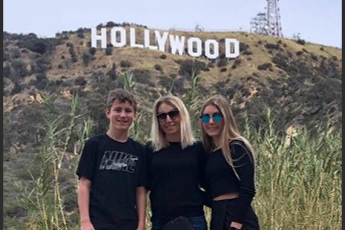 eine Gruppe von Menschen steht vor einem Hollywood-Schild