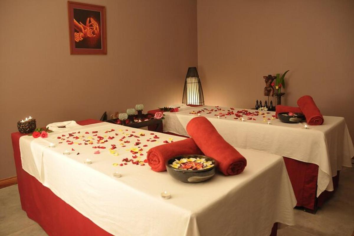 Dos camas con almohadas rojas y un jarrón de flores.
