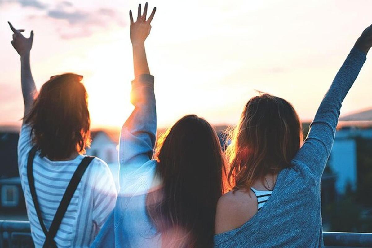 مجموعة من ثلاث فتيات يرفعن أيديهن في الهواء
