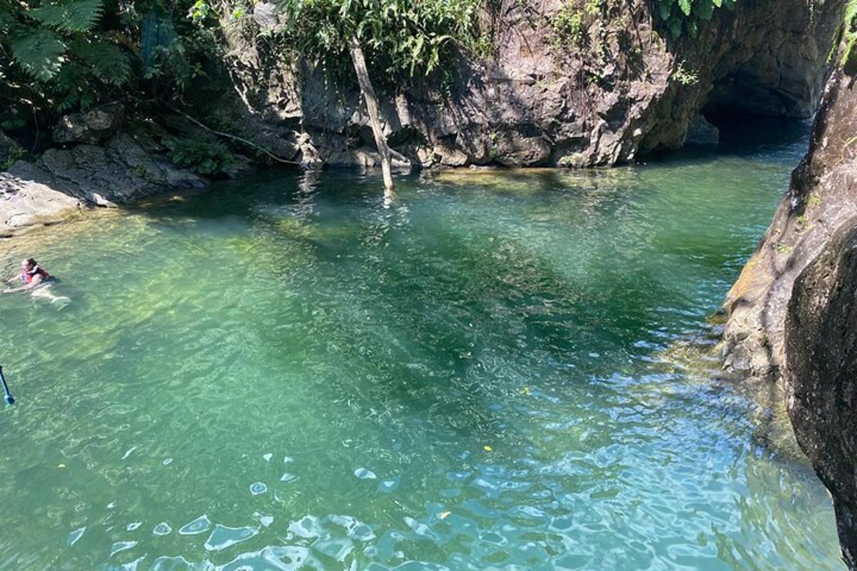 eine Person, die in einem Fluss neben einer Klippe schwimmt