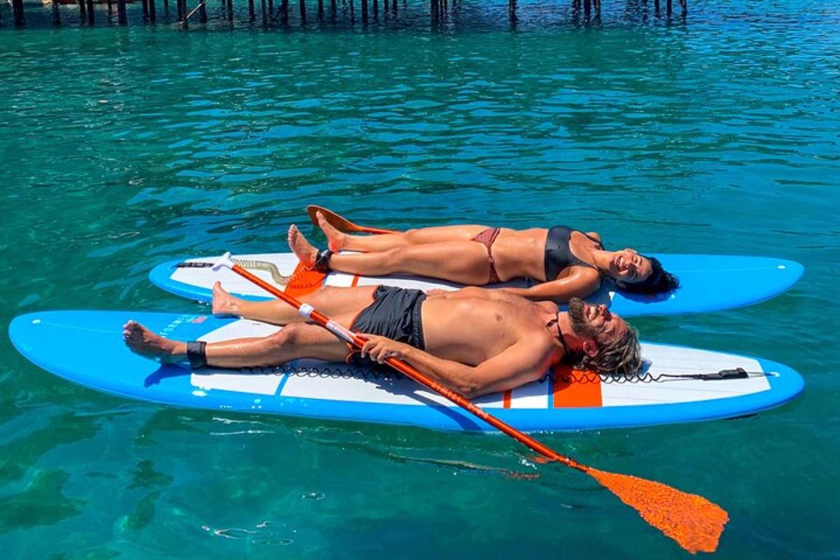 dva lidé ležící na paddleboardech ve vodě