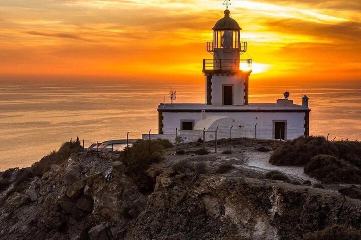 un far dalt d'un turó amb la posta de sol al fons