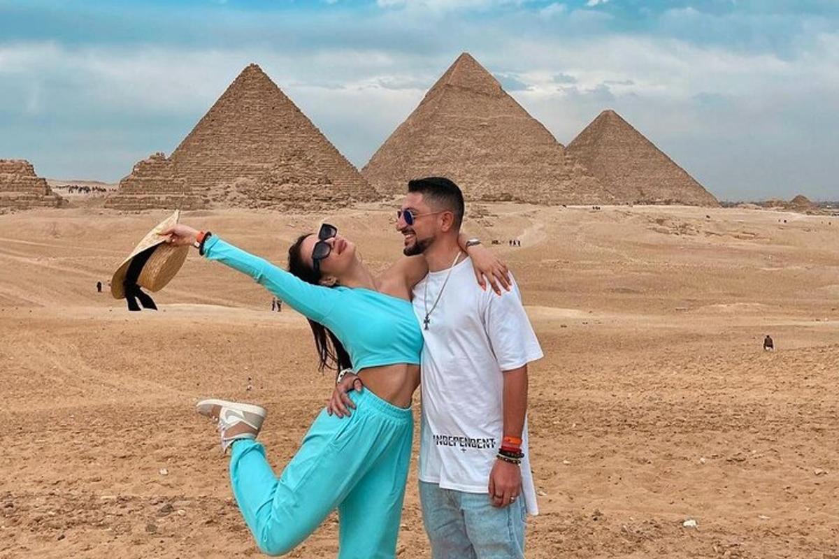 um homem e uma mulher posando em frente às pirâmides