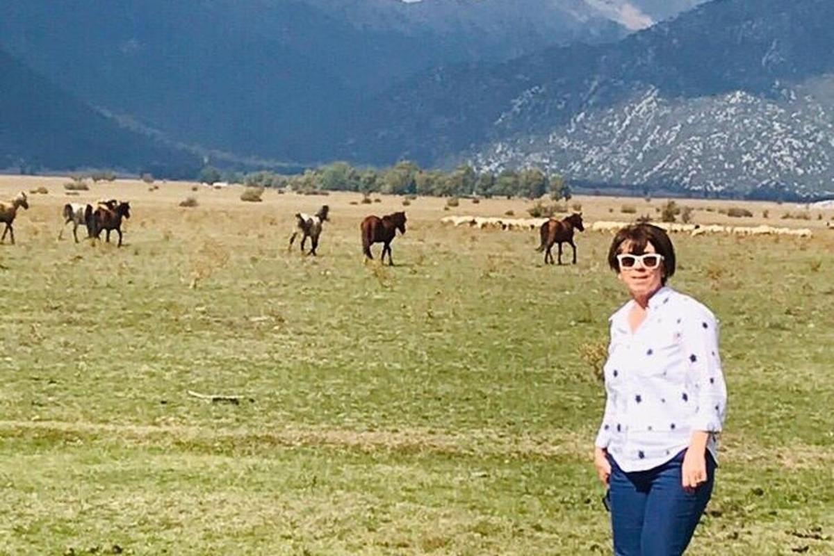 una donna in piedi in un campo con una mandria di cavalli