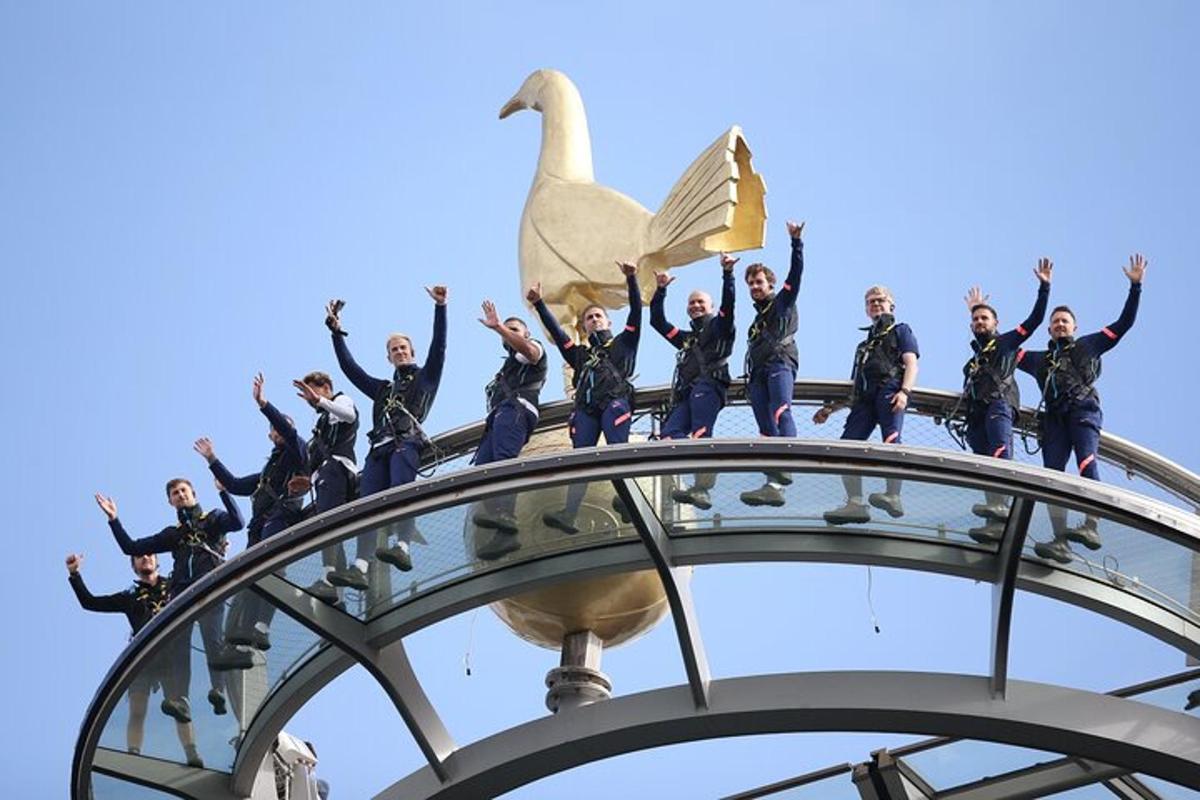 un grup de oameni care stau deasupra unei clădiri cu o lebădă