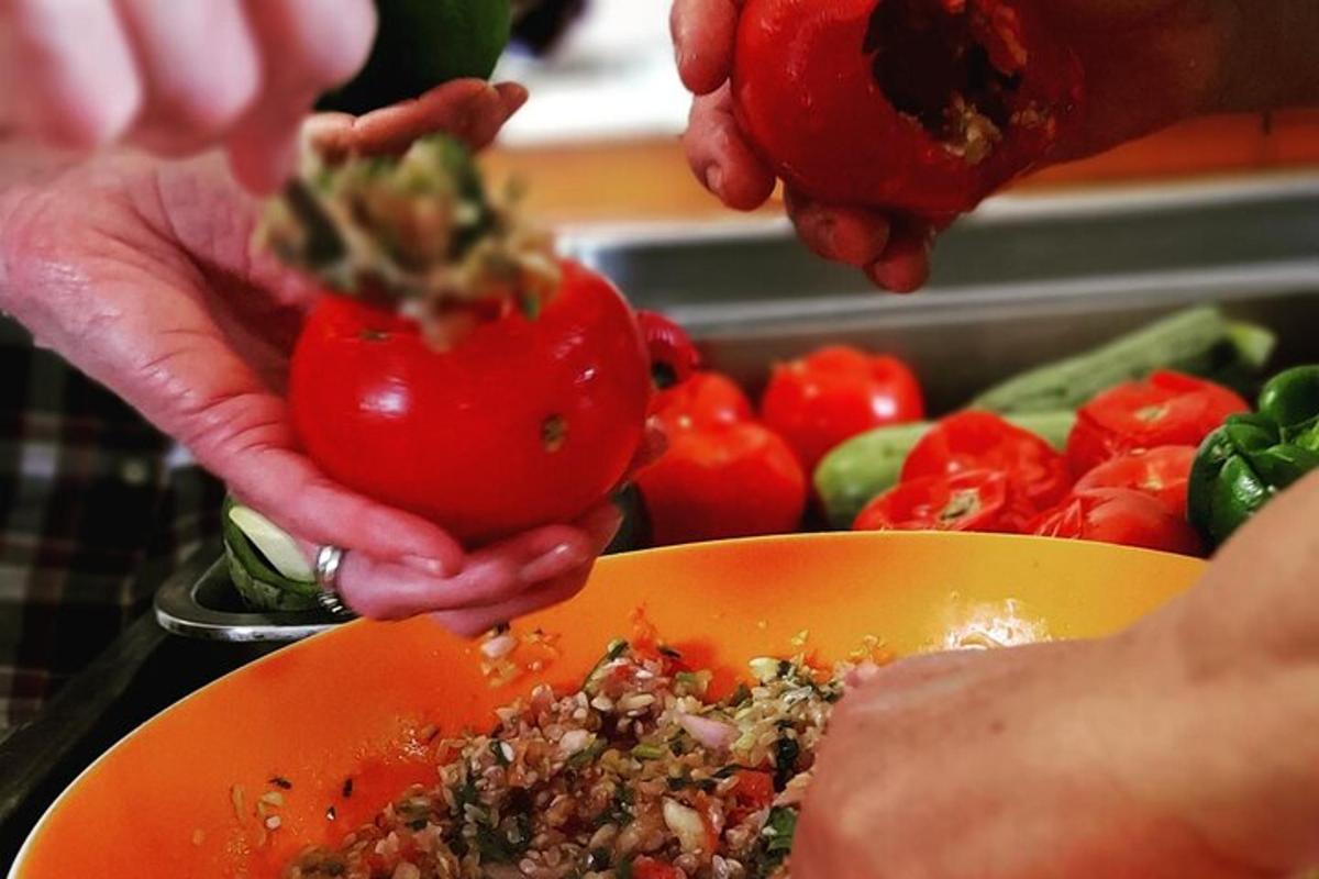 una persona sosteniendo un tomate en un tazón de verduras