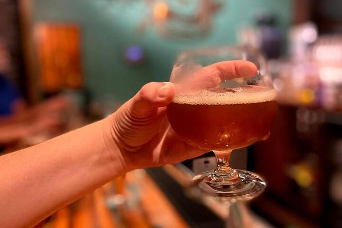 a person holding up a glass of beer