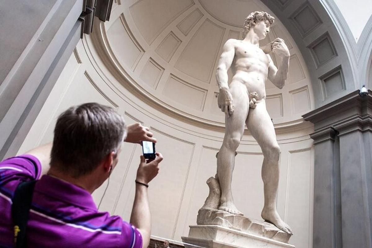 un home fent una foto d'una estàtua en un museu