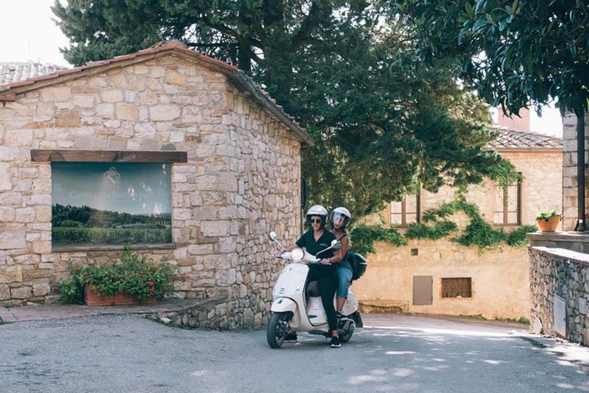 Dos personas conduciendo una scooter frente a un edificio de piedra.