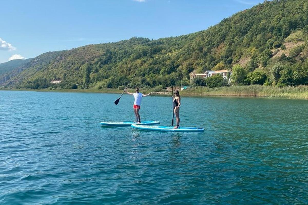 két ember áll a vízben evezős deszkákon