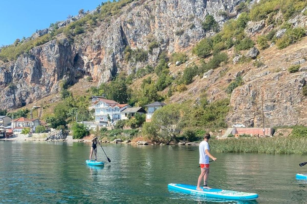 to personer står på paddleboards i vandet