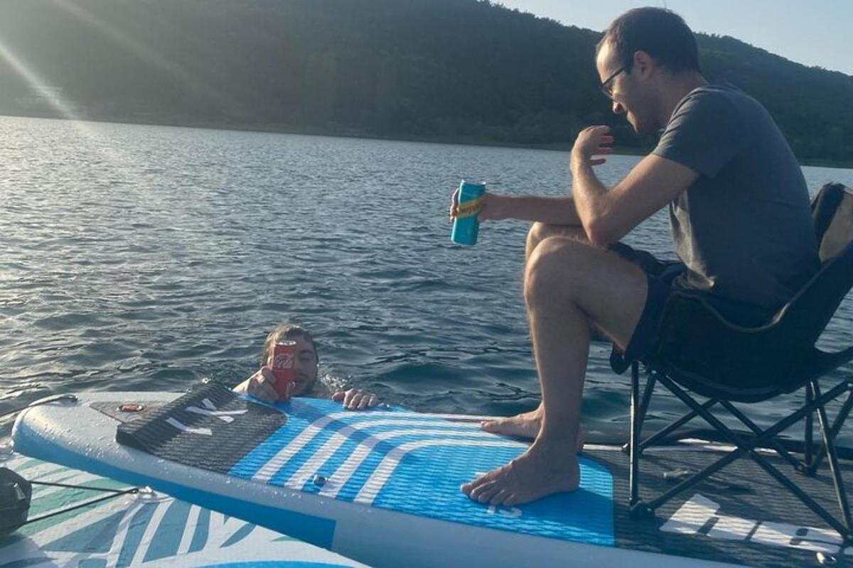 egy férfi ül egy SUP deszkán a vízben