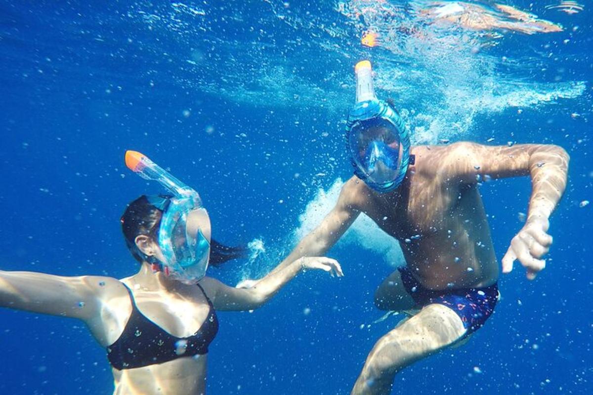 dua orang memakai topeng sedang berenang di dalam air