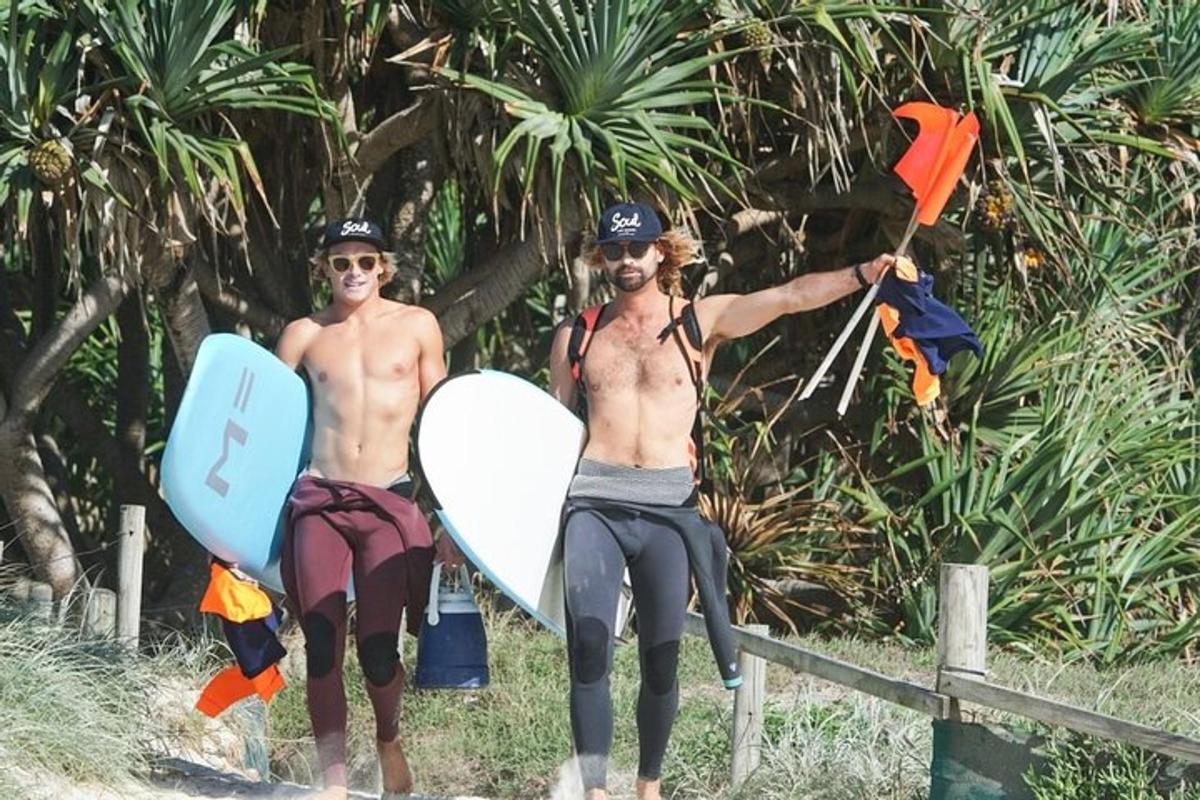 two men are standing on the beach with their surfboards