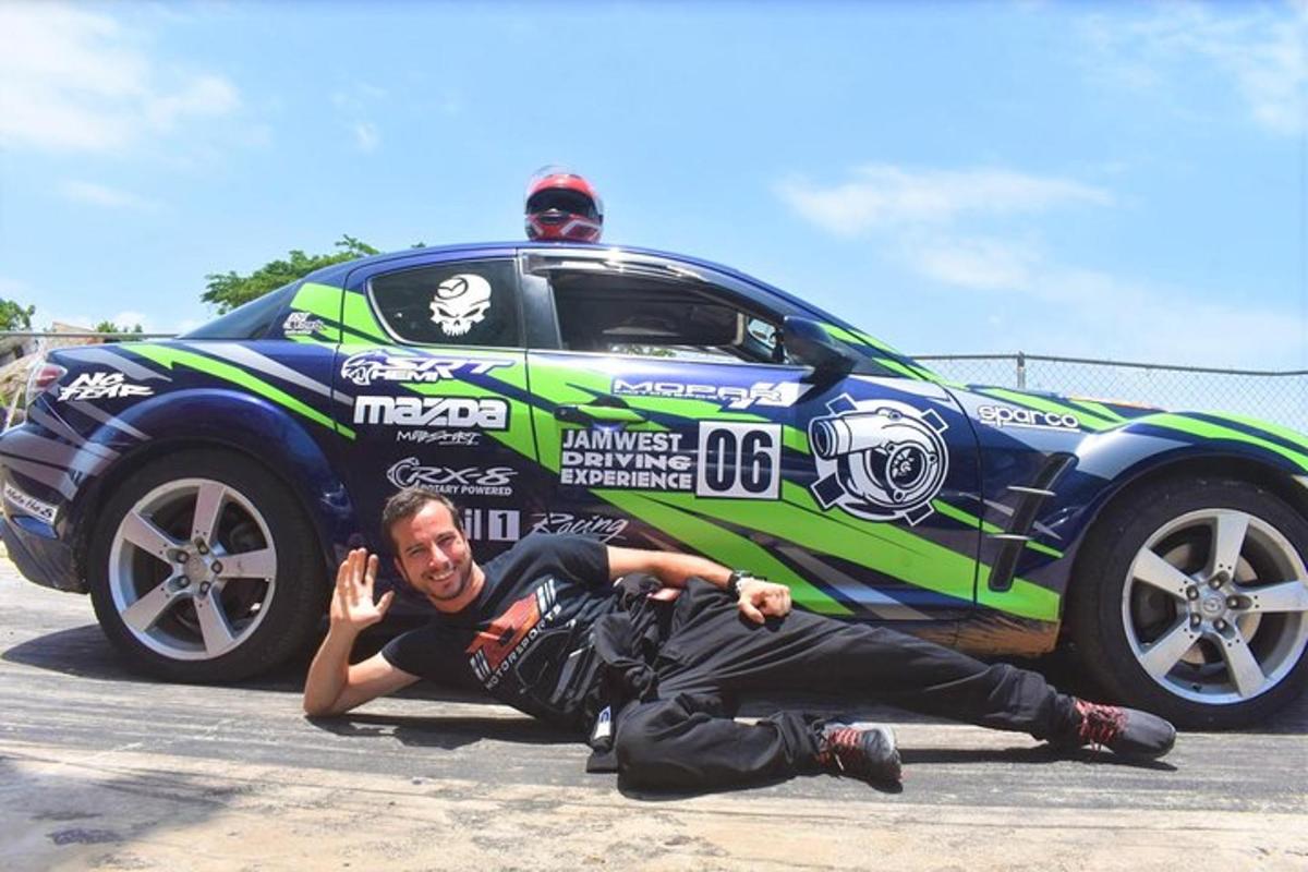 a man laying on the ground next to a race car