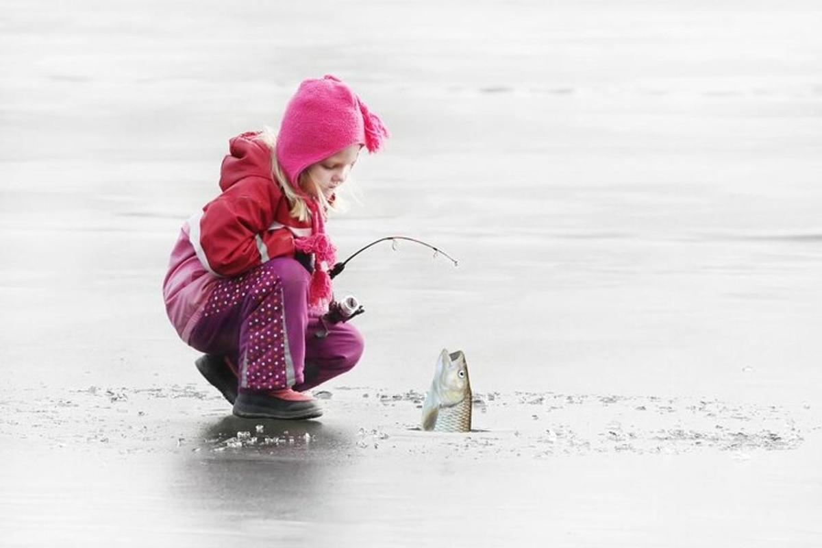 una bambina che gioca con un pesce sulla spiaggia
