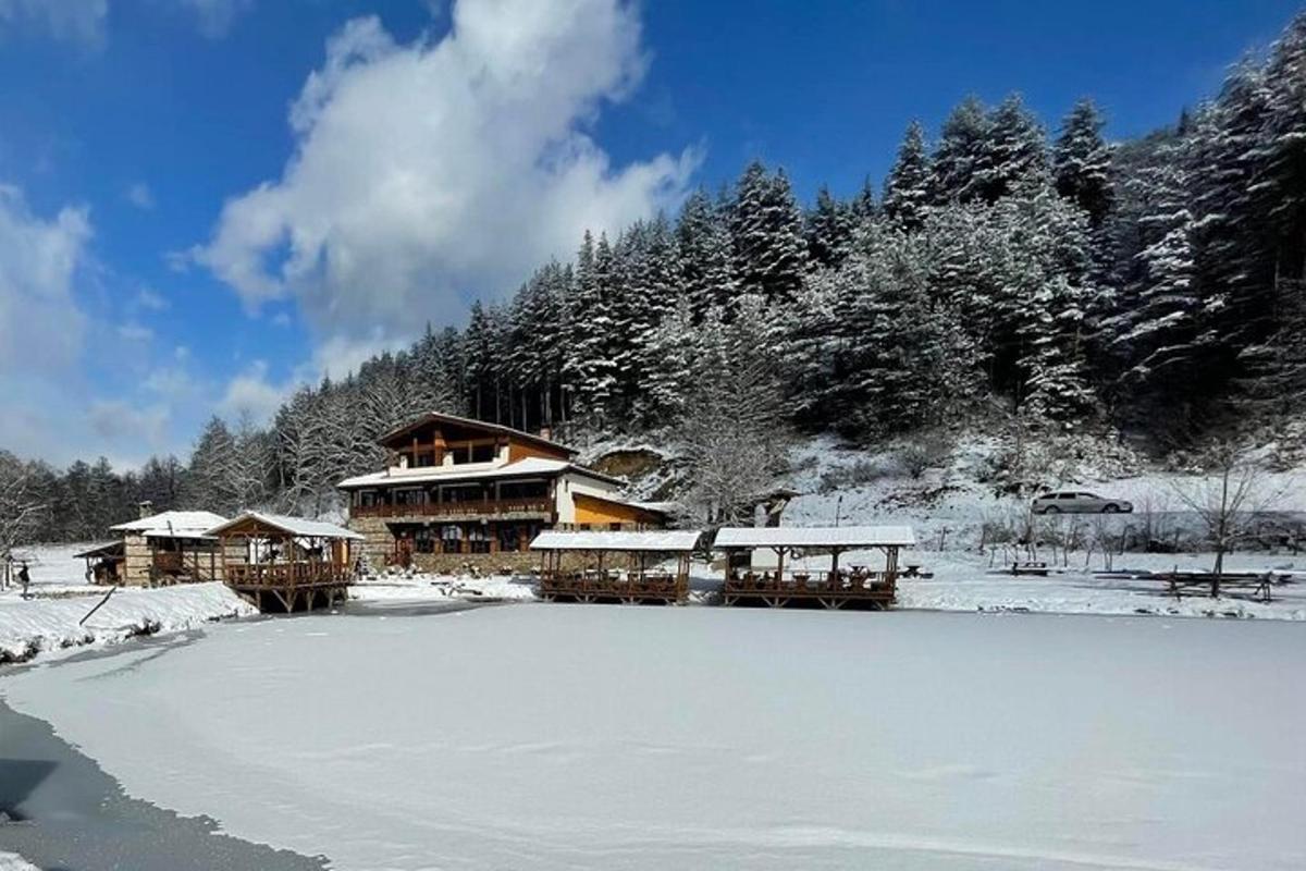 un rifugio sciistico con la neve sul terreno accanto a un lago