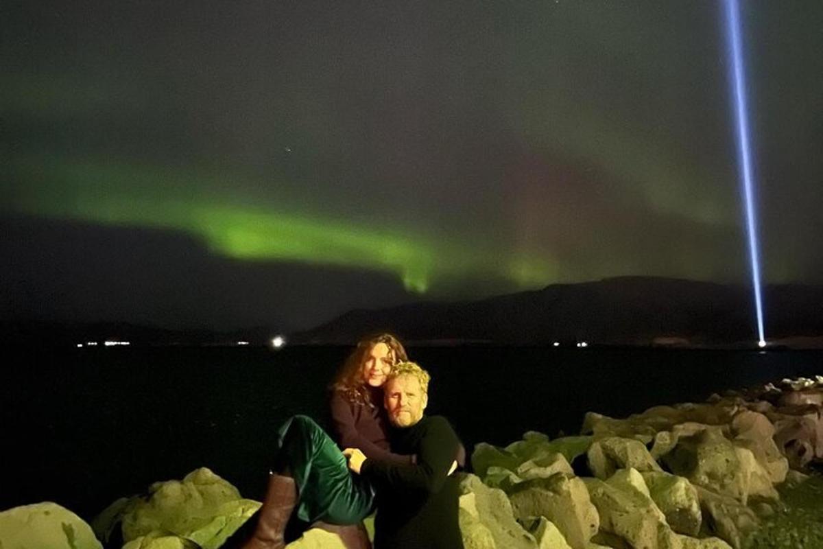 un uomo e una donna seduti sulle rocce sotto l'aurora