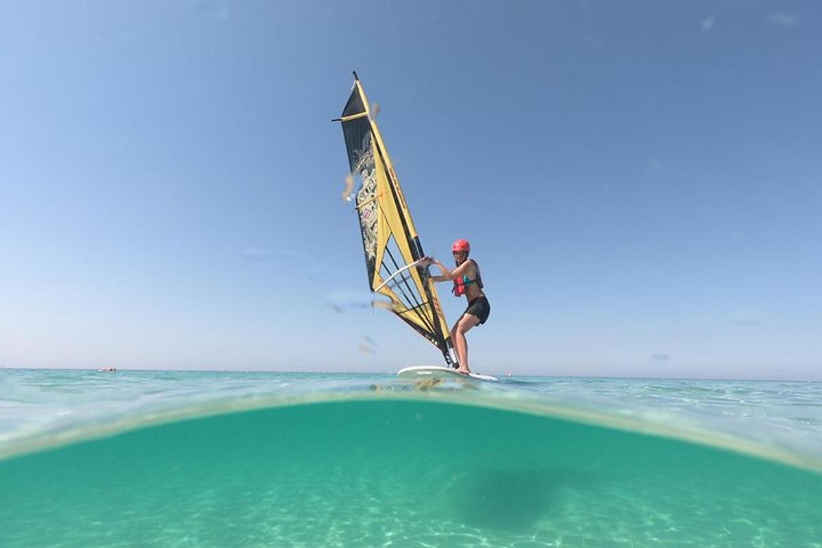 um homem em uma prancha de surfe com uma vela no oceano