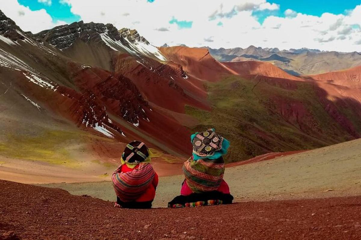 dues persones assegudes al desert mirant una muntanya